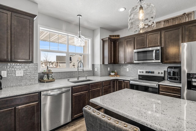 kitchen with tasteful backsplash, appliances with stainless steel finishes, dark brown cabinets, and a sink