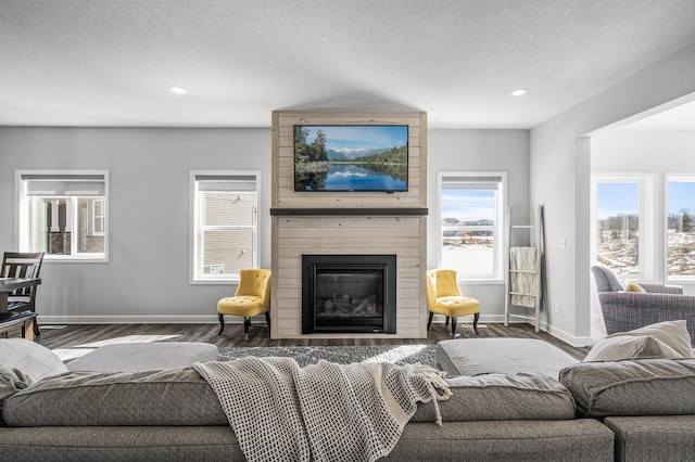 living area featuring a fireplace, recessed lighting, a textured ceiling, wood finished floors, and baseboards