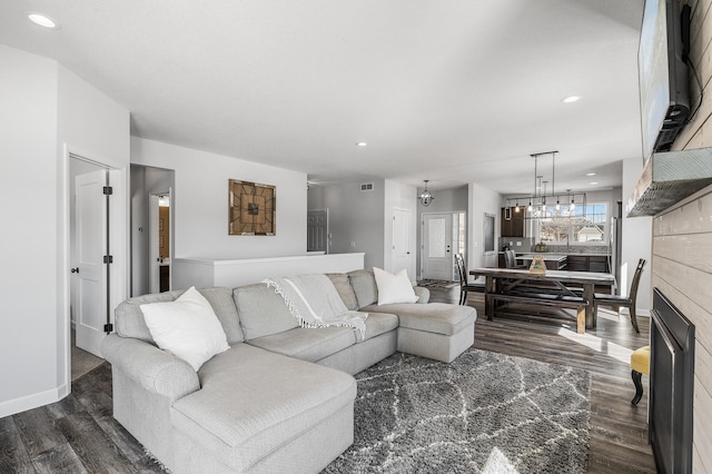 living room featuring dark wood-type flooring, recessed lighting, a chandelier, and baseboards