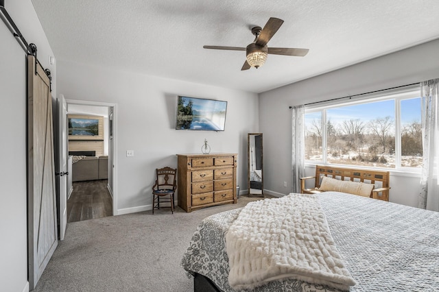 bedroom featuring a textured ceiling, carpet floors, a barn door, and baseboards