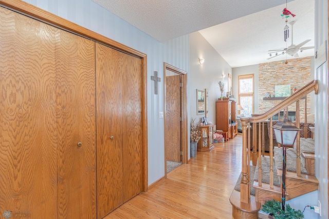 hall featuring light wood-style floors, a textured ceiling, and stairs