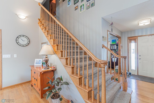 entrance foyer featuring stairs, a textured ceiling, baseboards, and wood finished floors