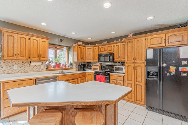 kitchen featuring light tile patterned floors, a sink, light countertops, backsplash, and black appliances