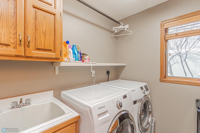 laundry area featuring a textured ceiling, independent washer and dryer, a sink, and cabinet space