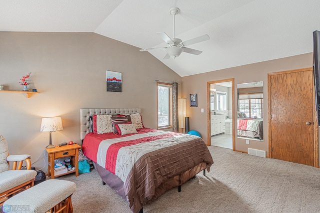 bedroom featuring carpet floors, visible vents, ensuite bathroom, vaulted ceiling, and ceiling fan