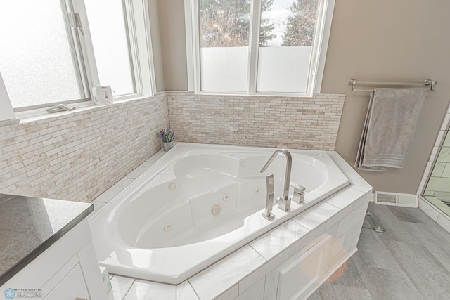 bathroom with a whirlpool tub, vanity, and visible vents