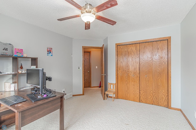 office with a textured ceiling, ceiling fan, baseboards, and light colored carpet