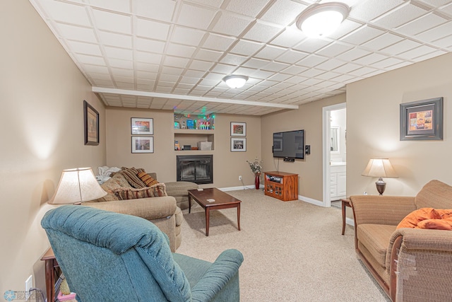 living room featuring baseboards, built in shelves, a glass covered fireplace, and light colored carpet