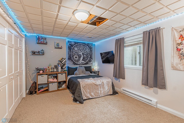 carpeted bedroom featuring a baseboard radiator, a closet, a paneled ceiling, and baseboards