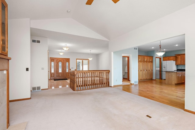 unfurnished living room with light carpet, lofted ceiling, visible vents, and baseboards