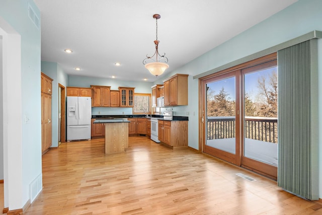 kitchen with light wood-type flooring, white appliances, glass insert cabinets, and a center island