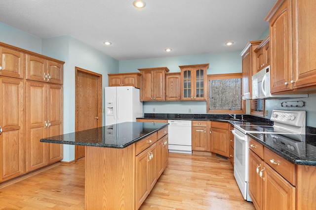 kitchen with white appliances, light wood-type flooring, glass insert cabinets, and a center island