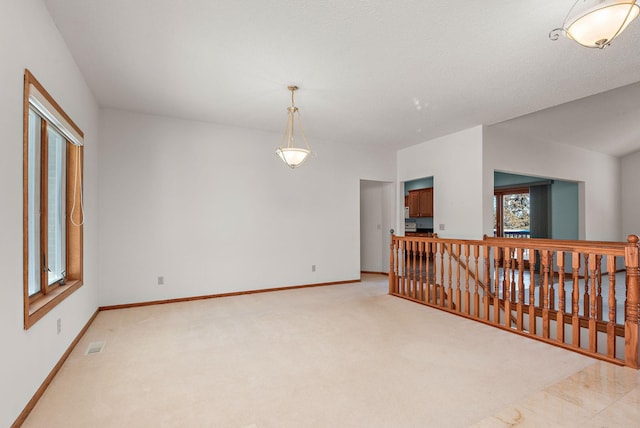 spare room featuring light carpet, plenty of natural light, visible vents, and baseboards