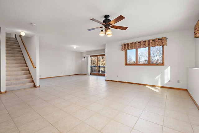 unfurnished room featuring baseboards, ceiling fan, stairs, a textured ceiling, and light tile patterned flooring