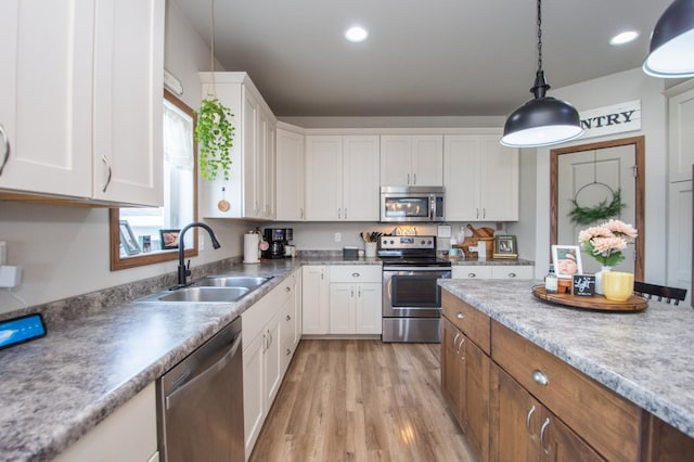 kitchen with light wood finished floors, a sink, white cabinetry, and stainless steel appliances
