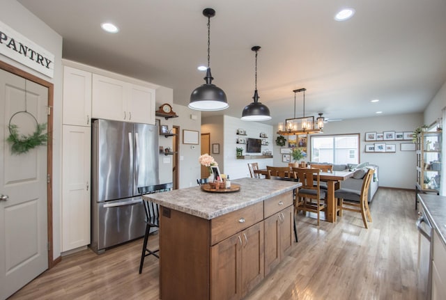 kitchen with decorative light fixtures, light wood-style floors, freestanding refrigerator, and a center island