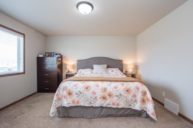 bedroom featuring baseboards, visible vents, and light carpet