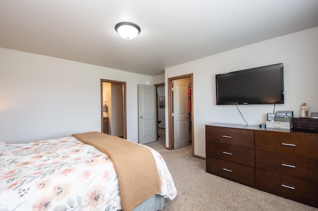 bedroom featuring a walk in closet, baseboards, light carpet, and a closet