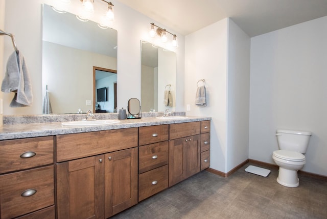 bathroom with toilet, double vanity, and a sink