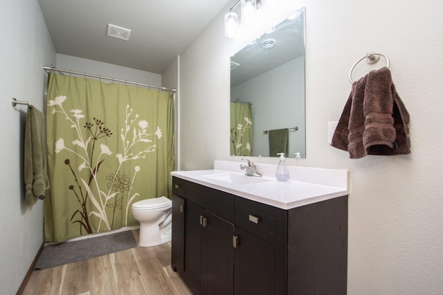 bathroom with toilet, wood finished floors, vanity, and visible vents