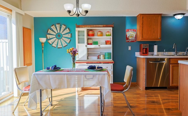 interior space with wood finished floors, stainless steel dishwasher, a sink, and brown cabinets