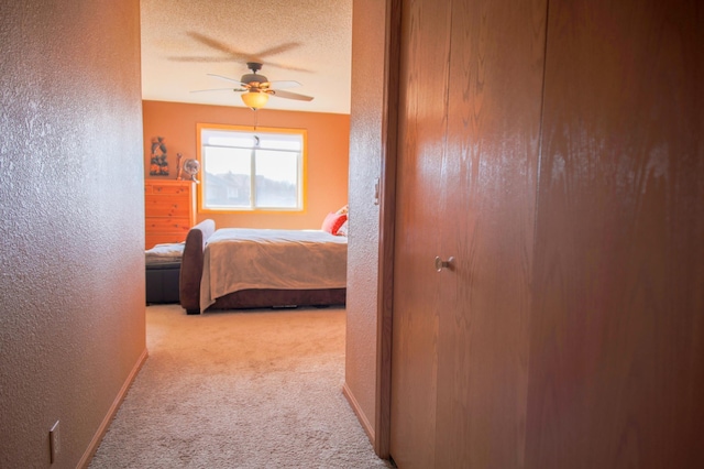 carpeted bedroom with a textured ceiling, a textured wall, ceiling fan, and baseboards