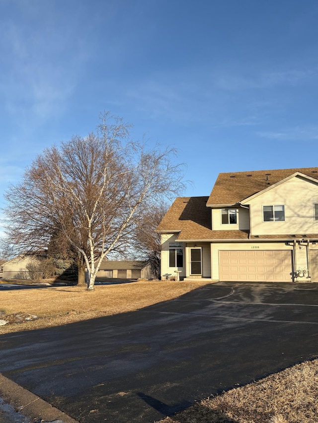 view of front of property featuring aphalt driveway, a shingled roof, and an attached garage