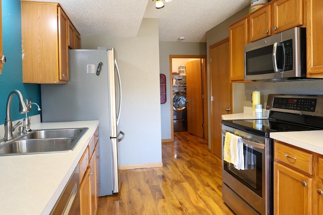 kitchen featuring light countertops, appliances with stainless steel finishes, a sink, and light wood-style flooring