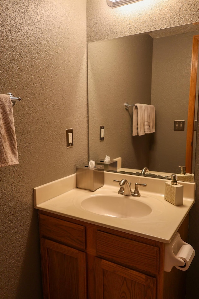 bathroom with a textured wall and vanity