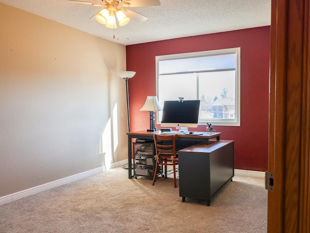 home office with a textured ceiling, a textured wall, carpet floors, a ceiling fan, and baseboards