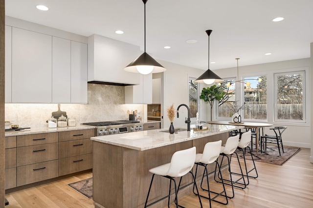 kitchen featuring stainless steel gas cooktop, white cabinets, modern cabinets, and light stone counters