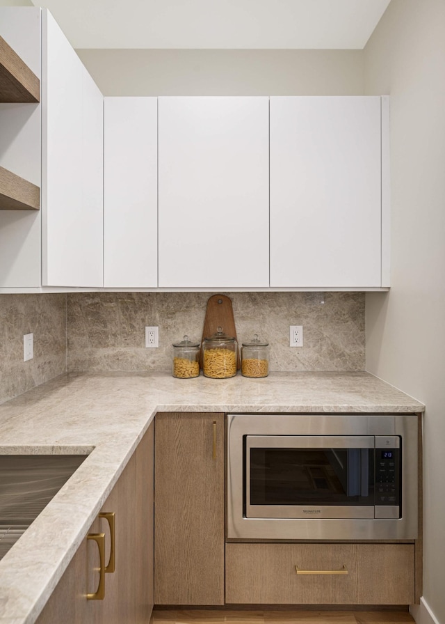 kitchen featuring stainless steel microwave, modern cabinets, and white cabinetry