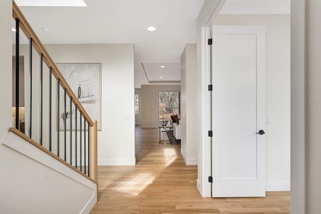 hall featuring recessed lighting, baseboards, light wood-style floors, and stairs