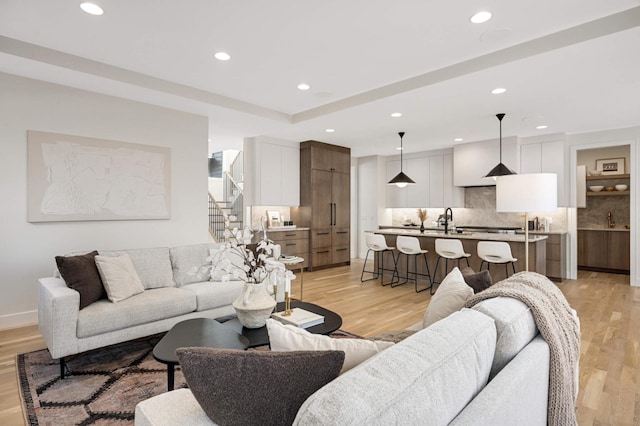 living area featuring recessed lighting, light wood-style flooring, stairway, and baseboards