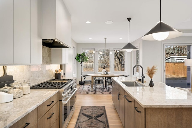 kitchen with double oven range, light wood-style flooring, a sink, modern cabinets, and tasteful backsplash