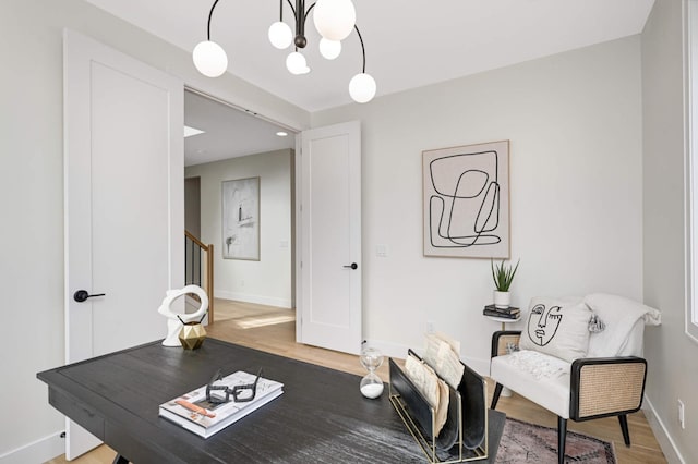 living area with a chandelier, baseboards, wood finished floors, and stairs