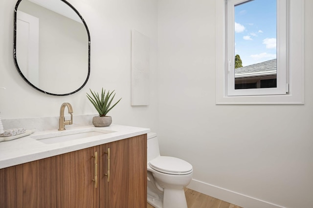 half bathroom featuring baseboards, toilet, wood finished floors, and vanity