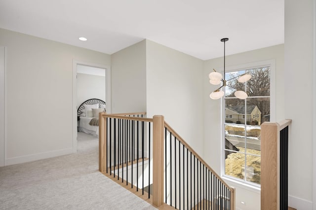 corridor featuring baseboards, carpet floors, an upstairs landing, recessed lighting, and an inviting chandelier