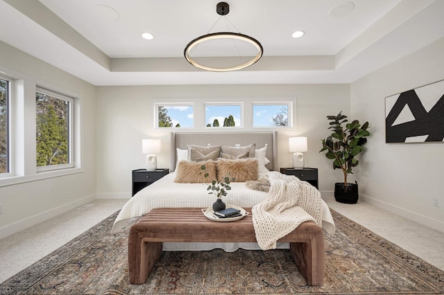 bedroom with multiple windows, a raised ceiling, carpet, and baseboards