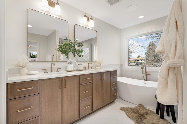 full bath with a wealth of natural light, marble finish floor, and a sink