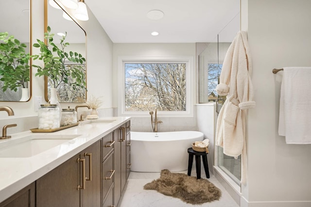 full bath with a soaking tub, double vanity, a shower stall, and a sink