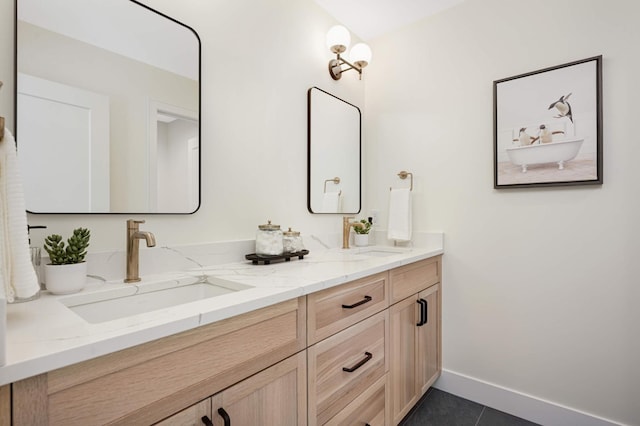 full bathroom featuring a sink, baseboards, double vanity, and tile patterned flooring