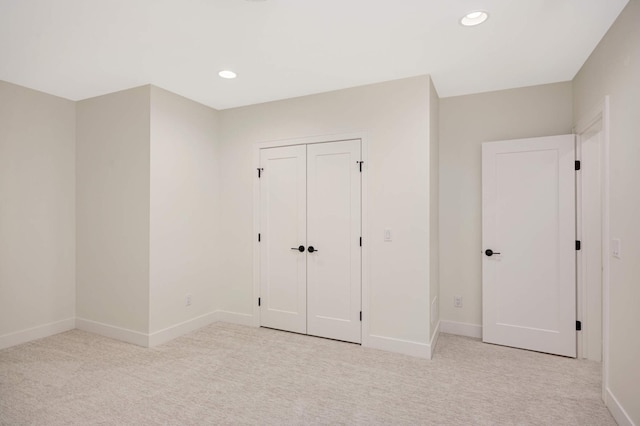 unfurnished bedroom featuring light carpet, recessed lighting, a closet, and baseboards