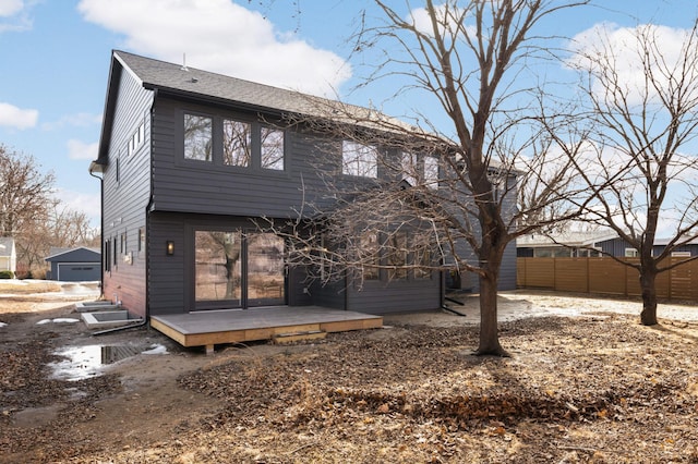 back of house featuring an outbuilding, fence, and a shingled roof