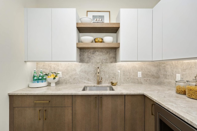 kitchen with a sink, tasteful backsplash, white cabinets, and light countertops