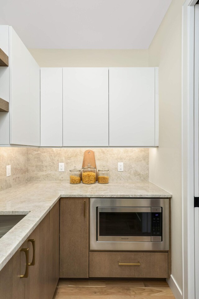 kitchen featuring stainless steel microwave, white cabinets, and modern cabinets