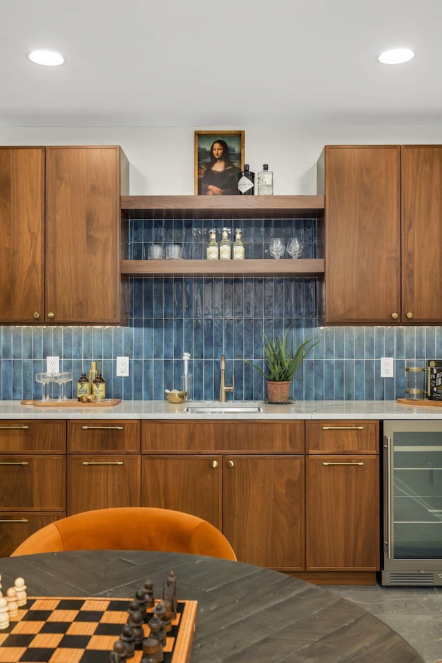kitchen with open shelves, wine cooler, light countertops, decorative backsplash, and a sink