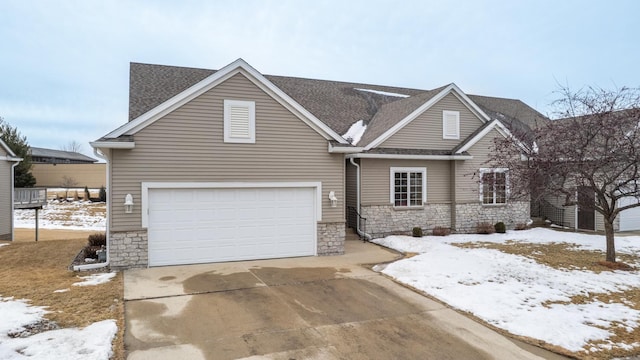 view of front of house with a garage, stone siding, driveway, and a shingled roof