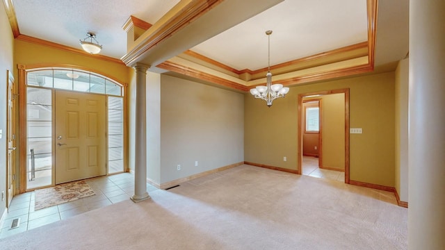 foyer with carpet floors, decorative columns, ornamental molding, and a raised ceiling