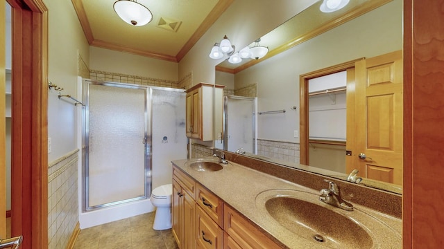 full bathroom with crown molding, a stall shower, wainscoting, and a sink